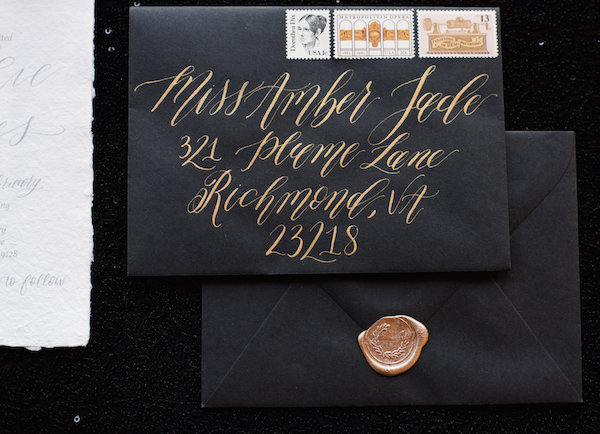 Gold hand lettering on a black envelope 