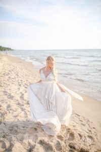 Bride on Lake Michigan beach twirling her dress in the wind