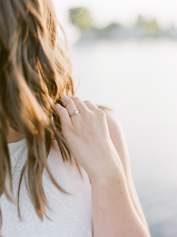 Engagement ring on the finger of a girl in a white dress