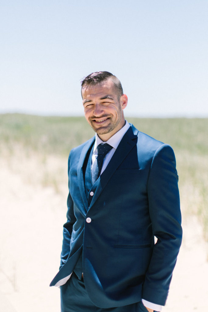 Groom standing on the beach before his Lake Michigan beach wedding ceremony 