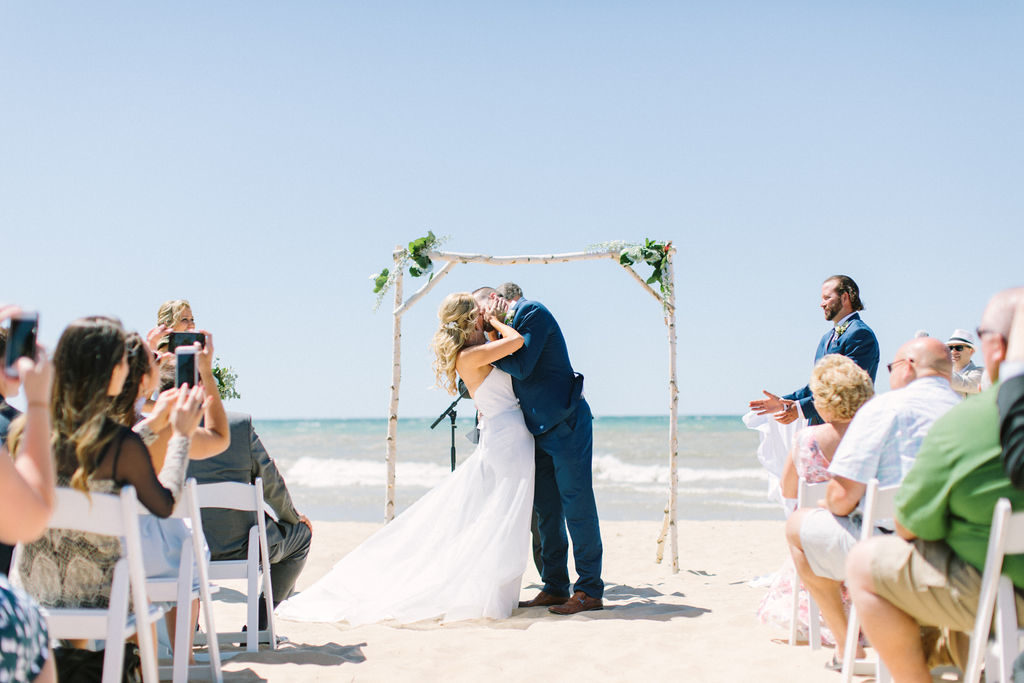 Bride and groom share their first kiss during their Lake Michigan beach ceremony
