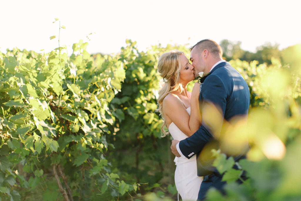 Couple kissing in the vineyard at a 12 Corners Vineyard Wedding