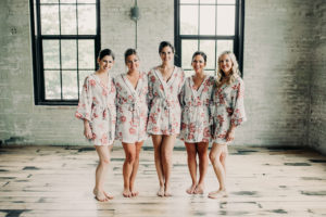 Bridesmaids smiling in robes before a wedding at Journeyman Distillery
