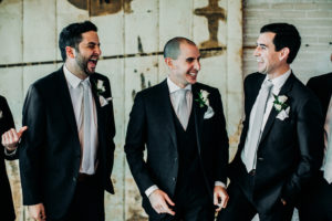 Groom and groomsmen smiling at a Journeyman Distillery wedding