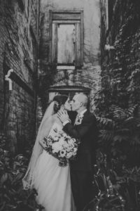 Bride and Groom kissing outside of Journeyman Distillery