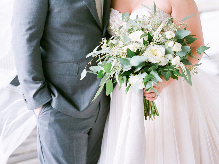 A bride holding a white and green bridal bouquet