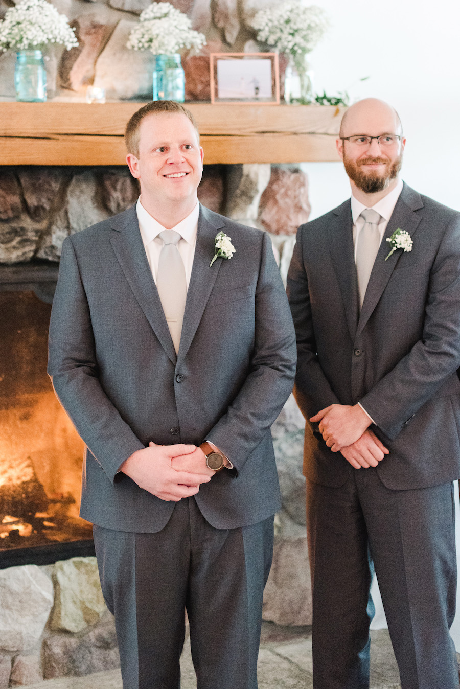 Groom smiling in front of the fire place at his camp blodgett wedding