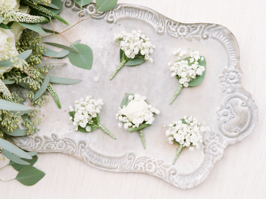 white boutonnières laid on silver tray