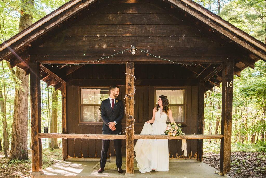 Newlyweds smiling outside the Honeymoon Cabin at their Long Lake Outdoor Center wedding