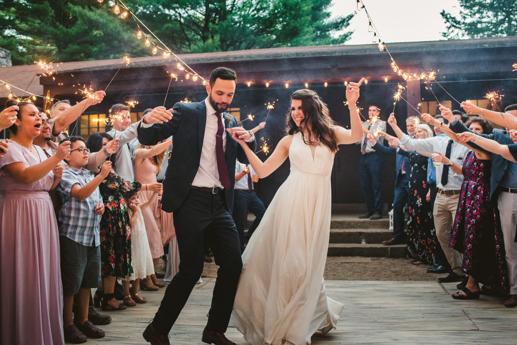 Bride and Groom smiling around sparklers at their Long Lake Outdoor Center wedding