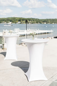 White cocktail tables set by the lake during a Bay Pointe Inn wedding in Shelbyville, Michigan