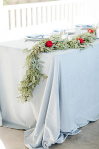 A blue velvet table linen with a fresh greenery garland at a Bay Pointe Inn wedding in Shelbyville, Michigan