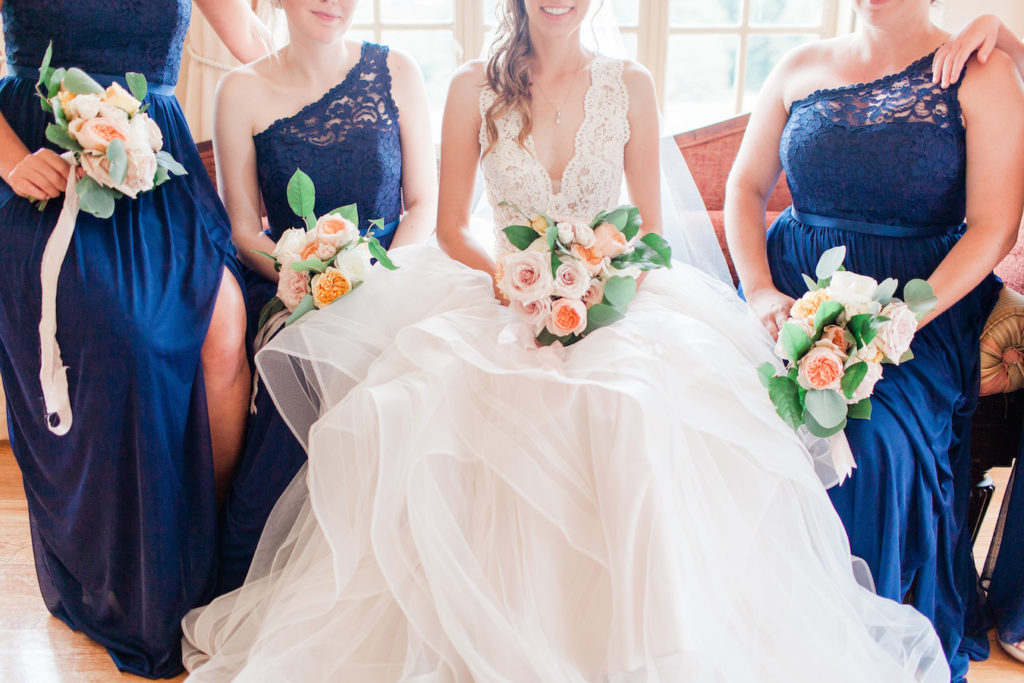 Bride and bridesmaids smiling with their bouquets before a felt mansion wedding