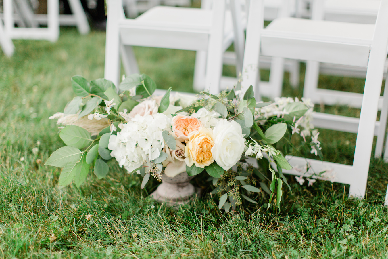 A large floral arrangement rests on the ground before a Holland, Michigan wedding