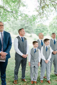 Groom and groomsmen smiling as the bride walks down the aisle at a felt mansion wedding