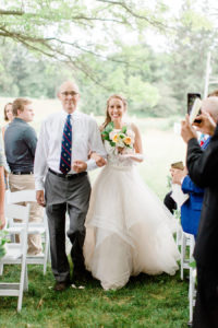 Bride and her father smiling as they walk down the aisle at her felt mansion wedding