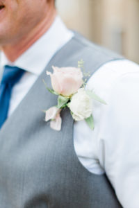 A blush and white groom's boutonnière pinned to his chest