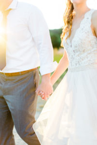 Bride and groom holding hands during sunset at their felt mansion wedding