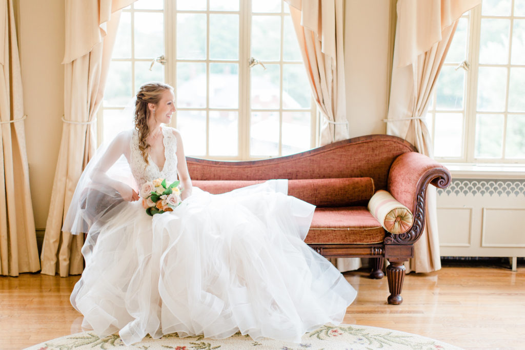 Bride smiling on a sofa in the bridal suite at her felt mansion wedding