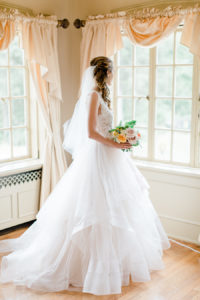 Bride looking out the window before her felt mansion wedding