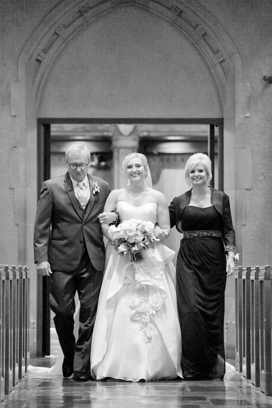 A bride walking down the aisle with her parents during her Kalamazoo, Michigan wedding