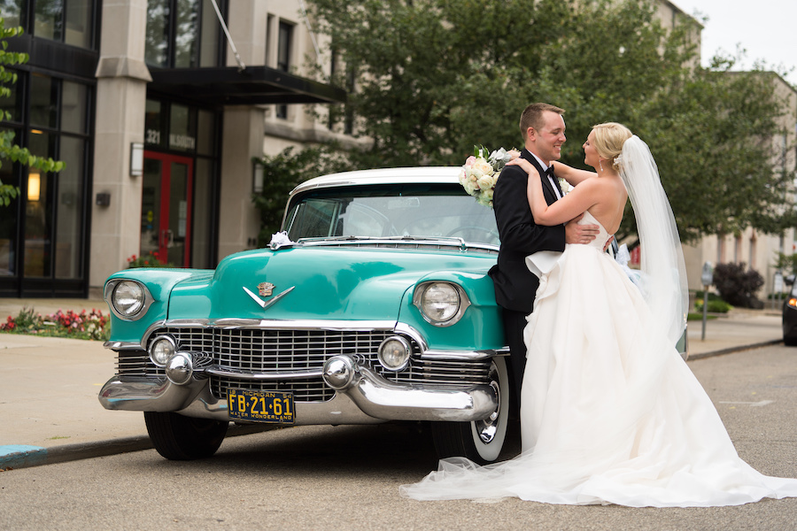 A bride and groom in front of a vintage car during their Kalamazoo, Michigan wedding