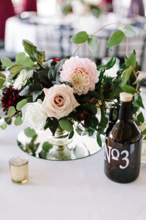 A blush and burgundy floral arrangement with a growler table number at a Loft 310 wedding