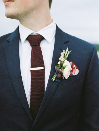 A groom with a navy suit and burgundy tie