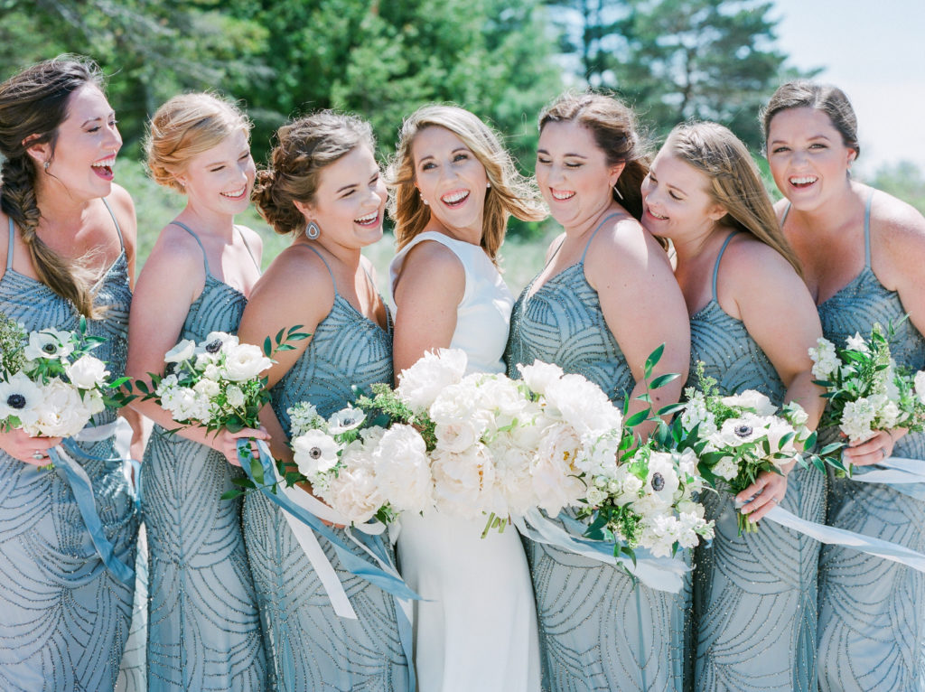 Bride and bridesmaids smiling before a Lake Michigan beach ceremony