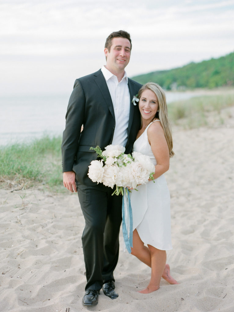 Bride and groom smiling on the beach after their Lake Michigan beach ceremony