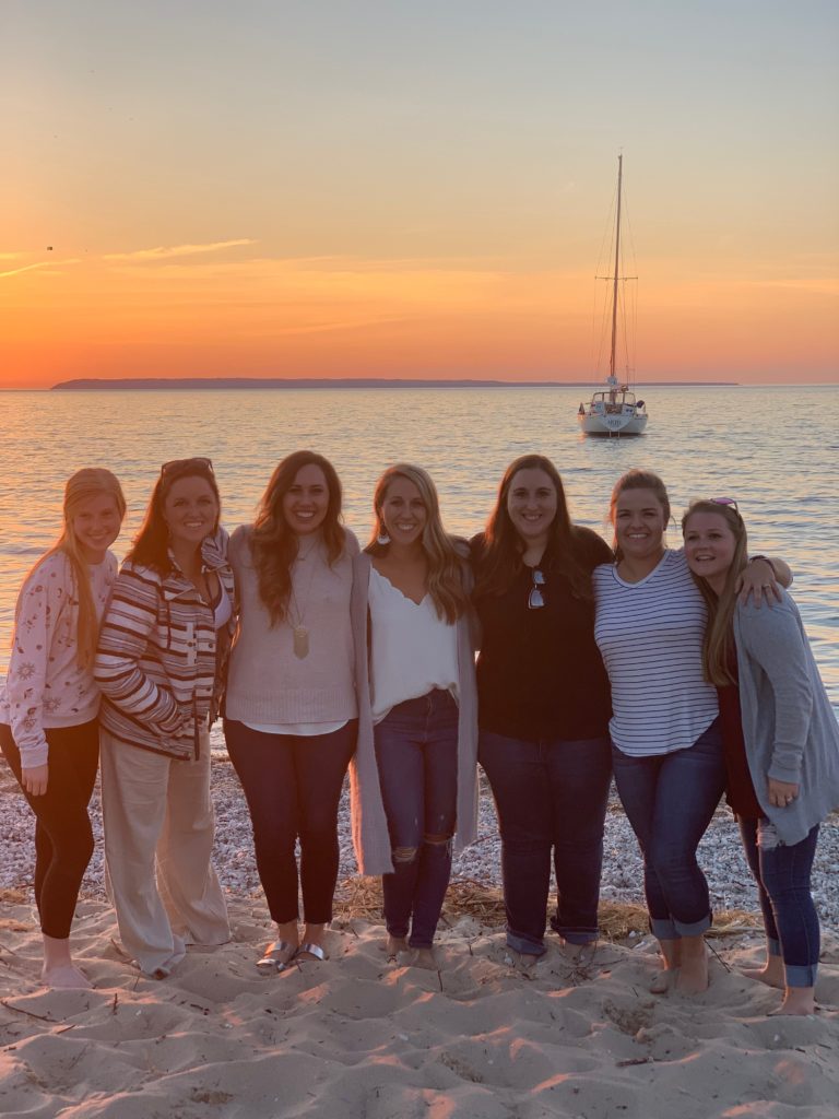 A group of ladies smiling during a sunset on Lake Michigan