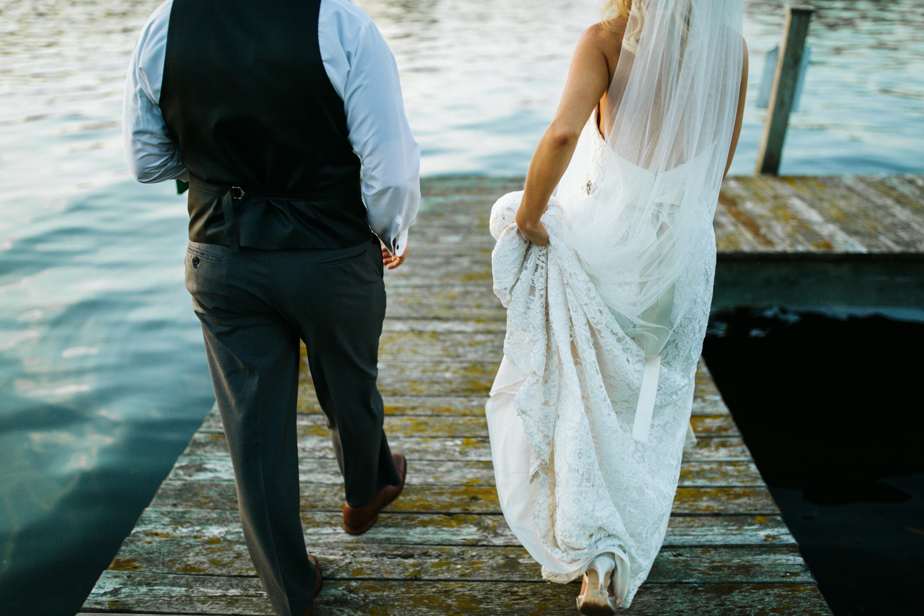 A bride and a groom walking by Spring lake during their spring lake country club wedding