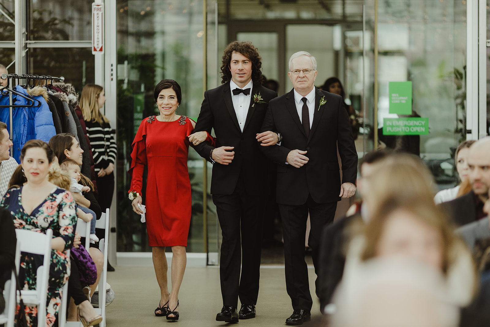 A groom walking his parents down the aisle