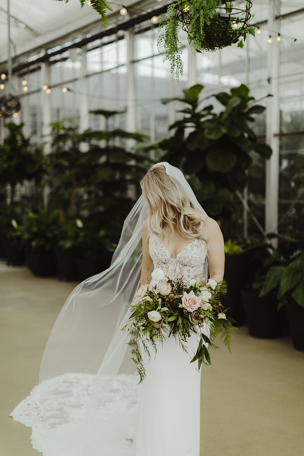 A bride smiling with her bouquet after her wedding ceremony