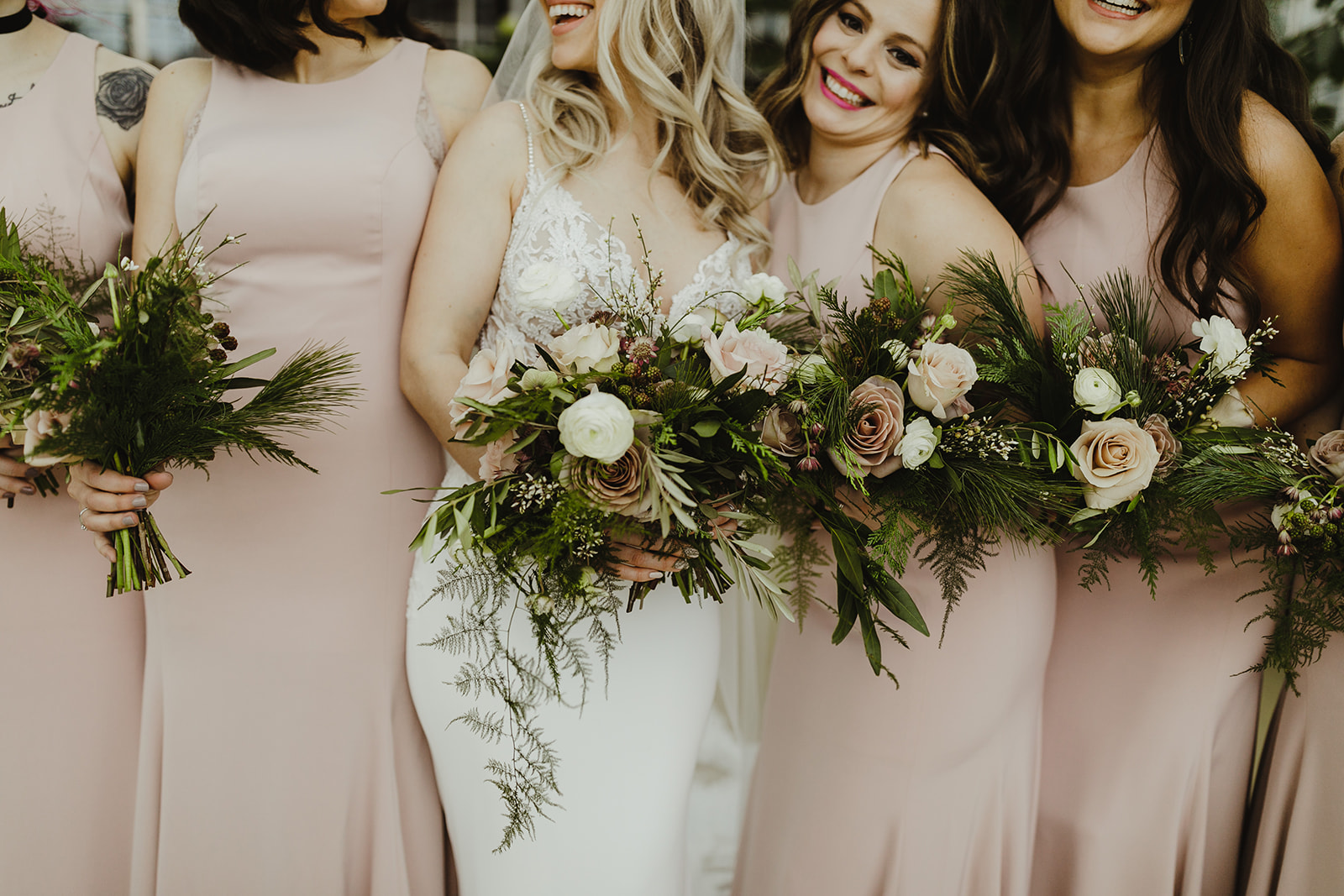 A bride and her bridesmaids smiling with their bouquets