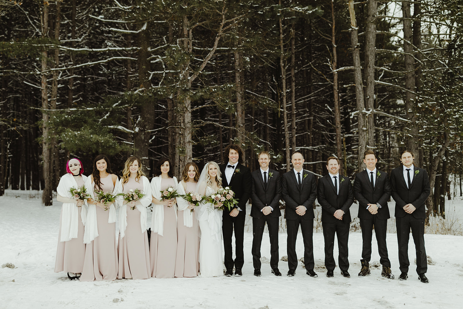 A wedding party smiling outside on a snowy Grand Rapids, Michigan day