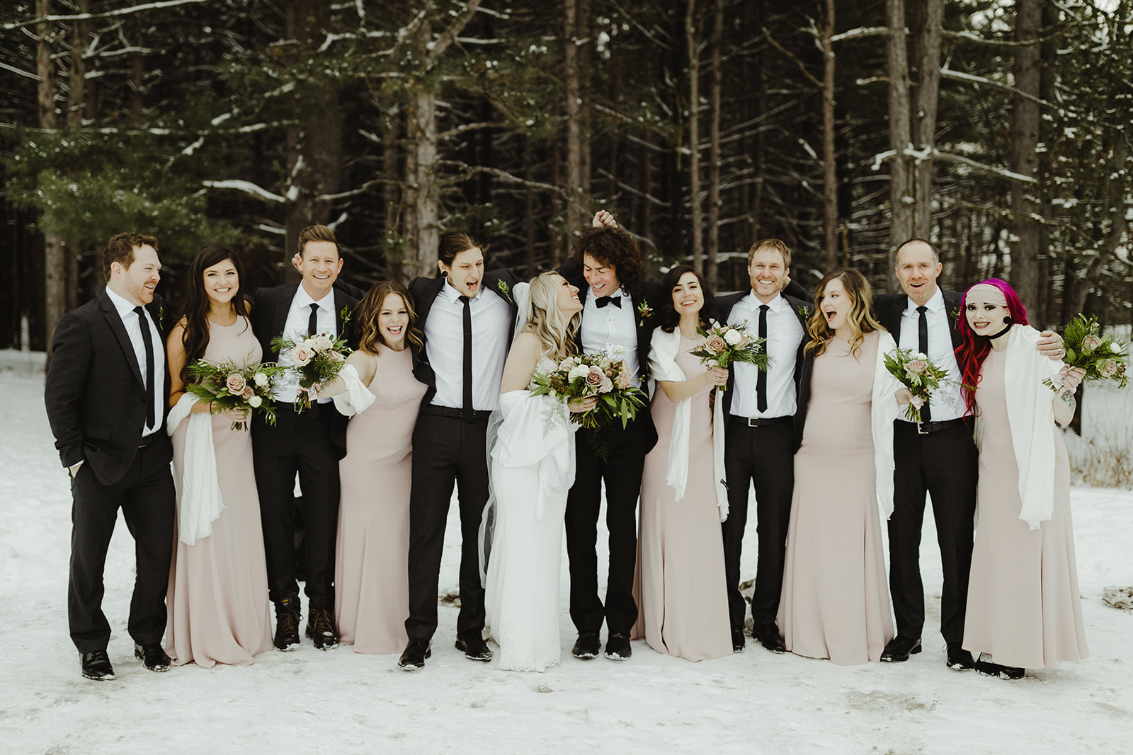 A wedding party smiling in the snow