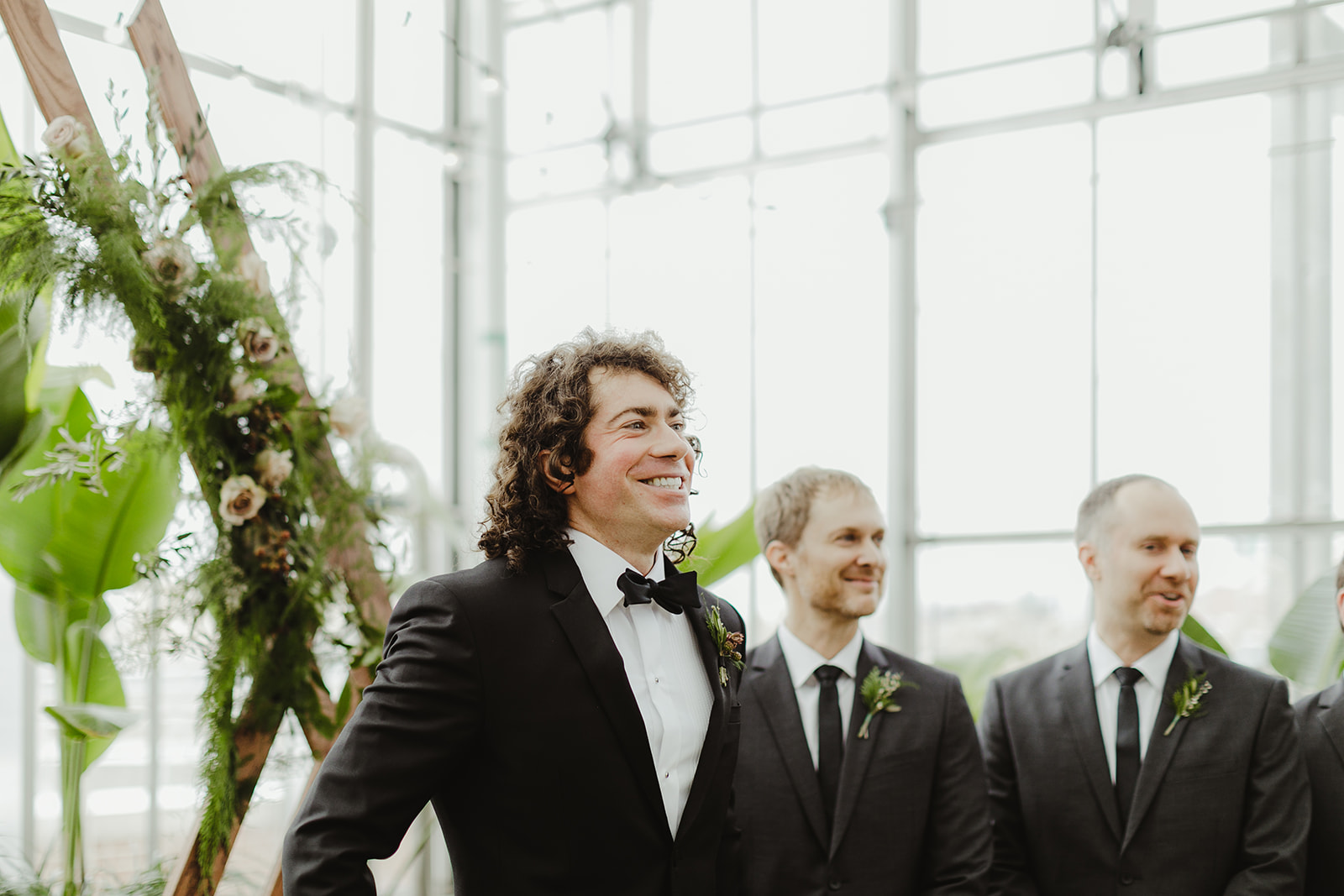 A groom smiling as his bride walks down the aisle