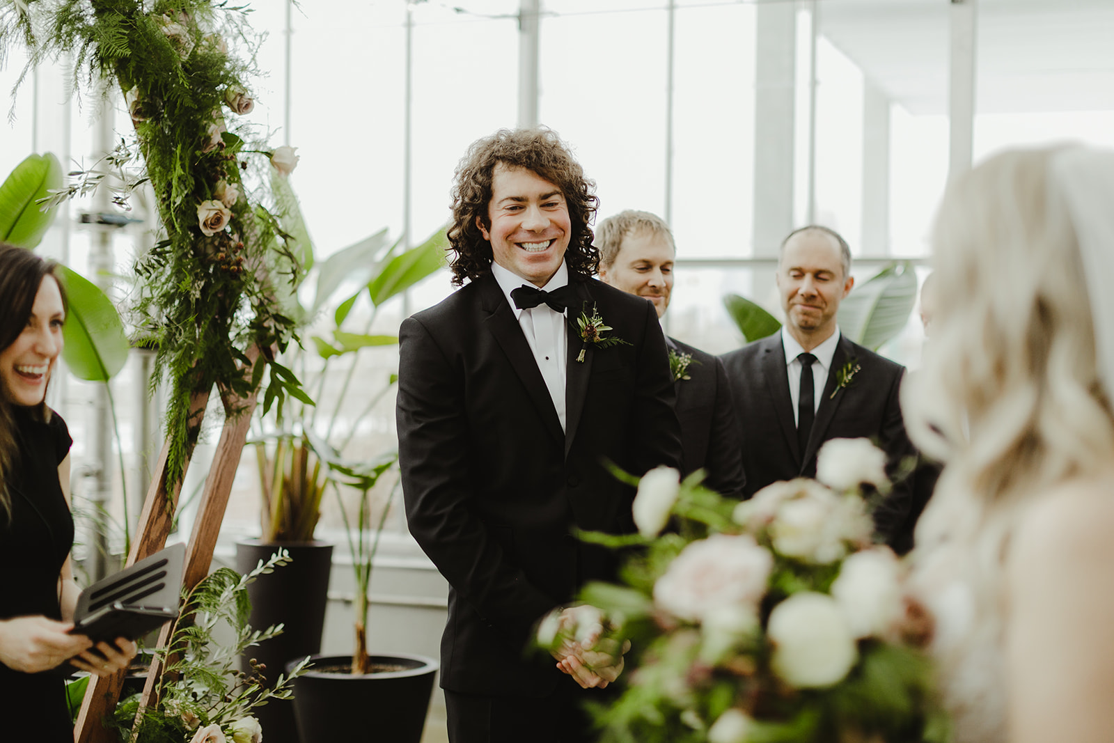 A groom smiling at his bride and she walks down the aisle