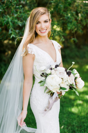 A bride smiling with her bouquet