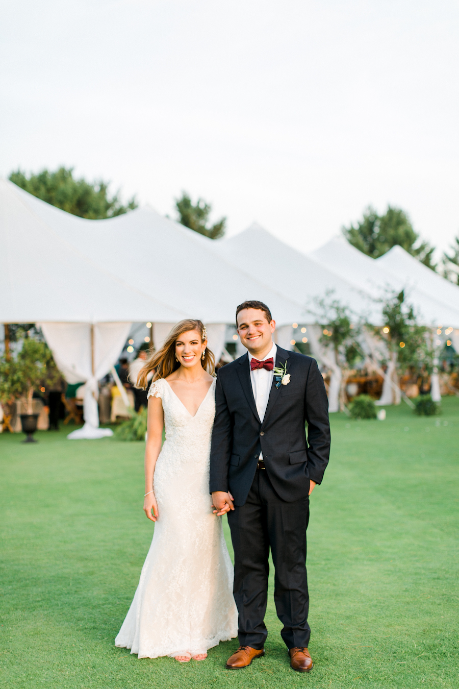 A couple smiling in front of their wedding tent 