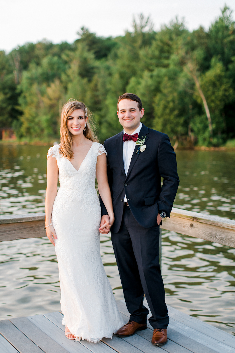 A couple smiling at the camera at their lakeside wedding