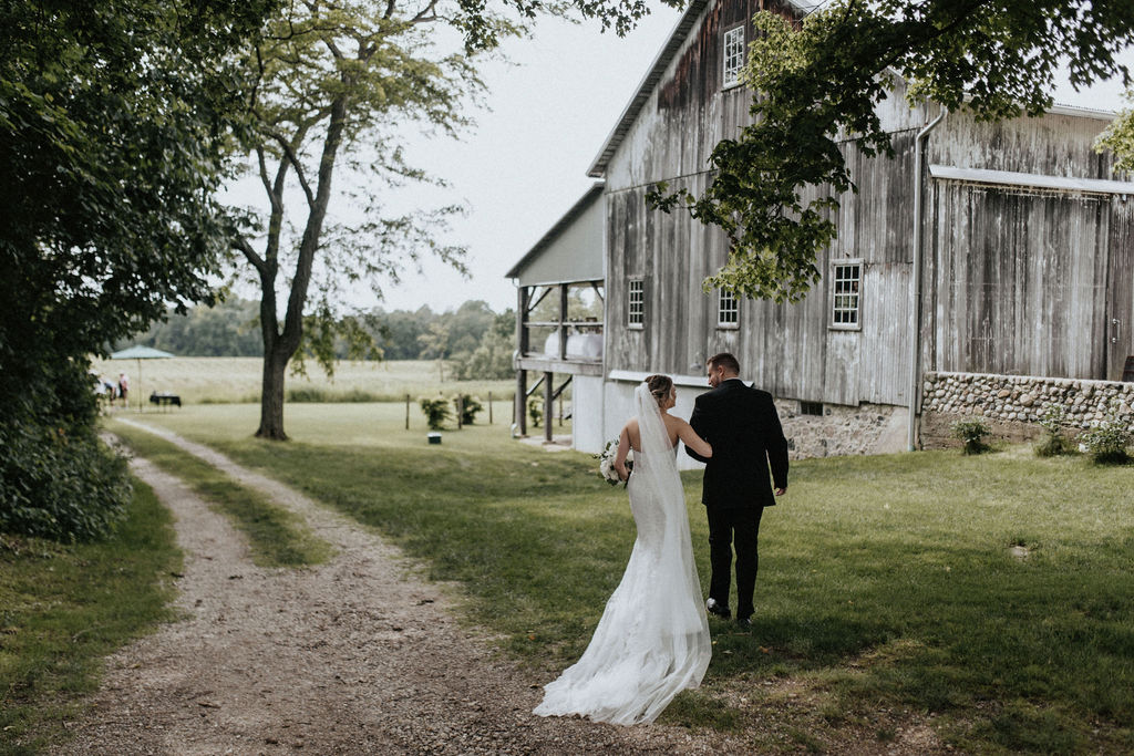 A couple walking to the barn during their Hidden Vineyard Wedding Barn wedding.