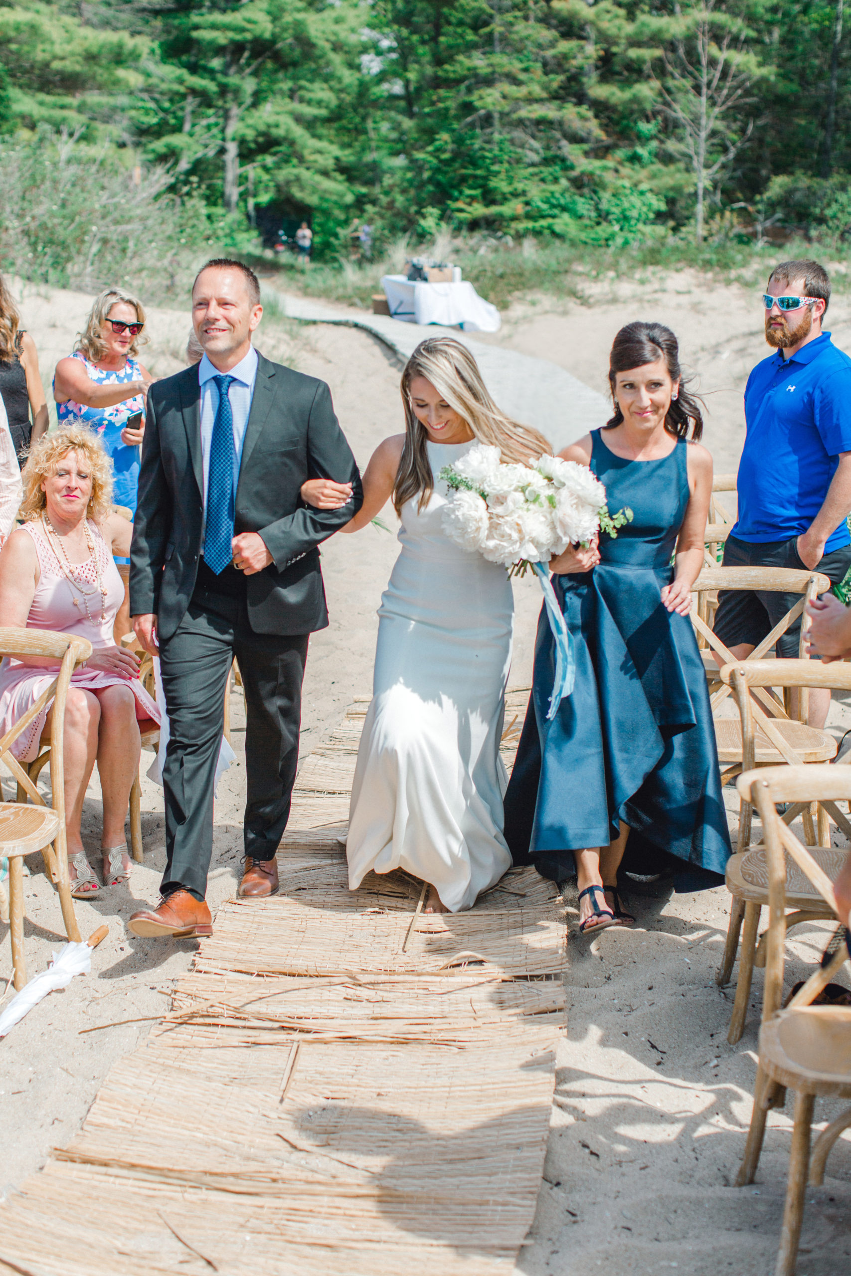 A bride and her parents during a beach wedding