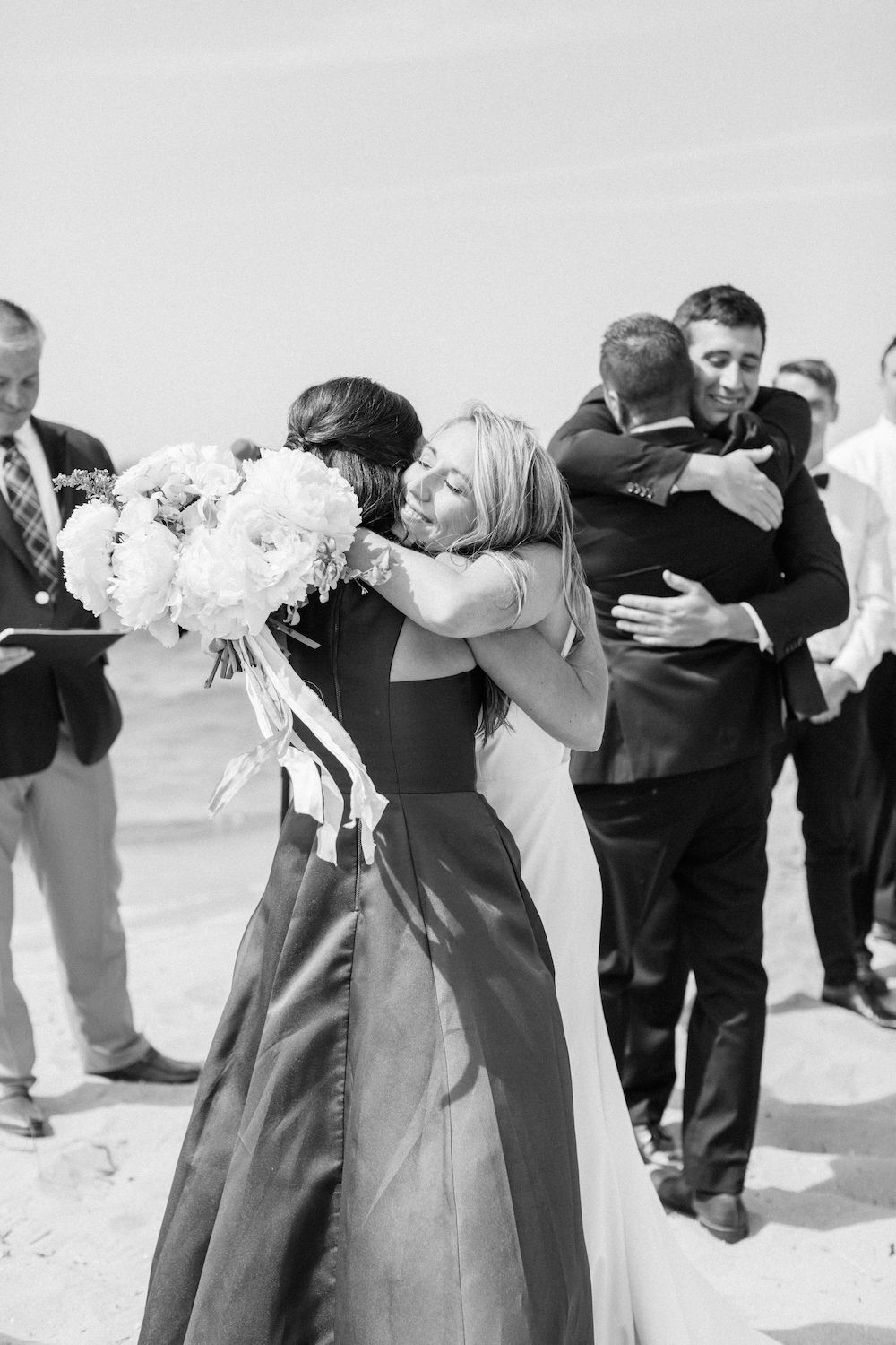 A couple hugging parents during their wedding