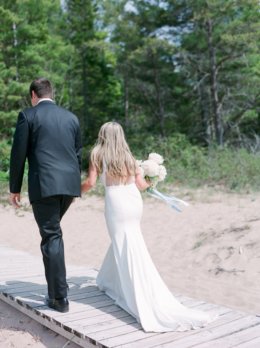 A couple walking off the beach after their wedding