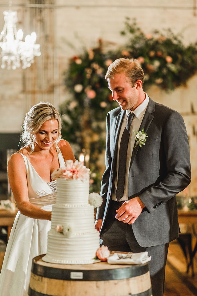 Bride and Groom smiling while cutting their cake
