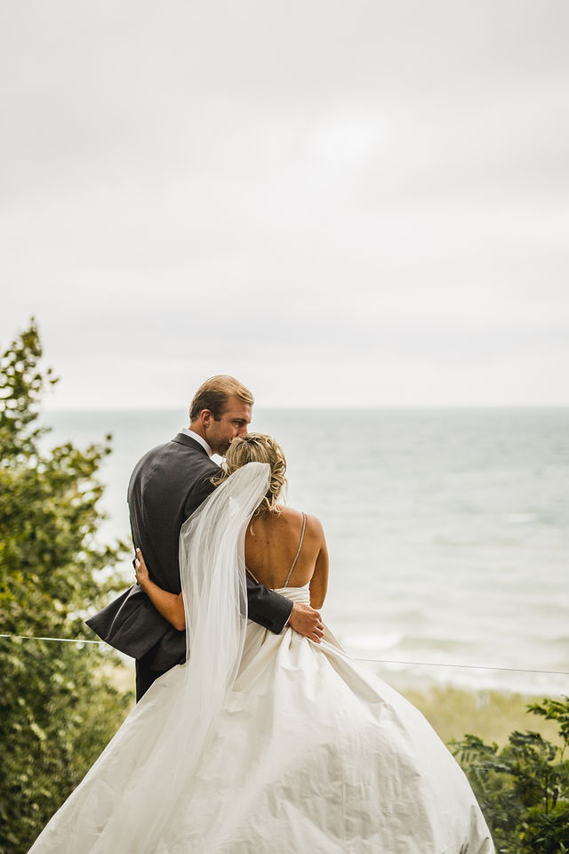 Groom kissing brides forehead with Southwest Michigan wedding background