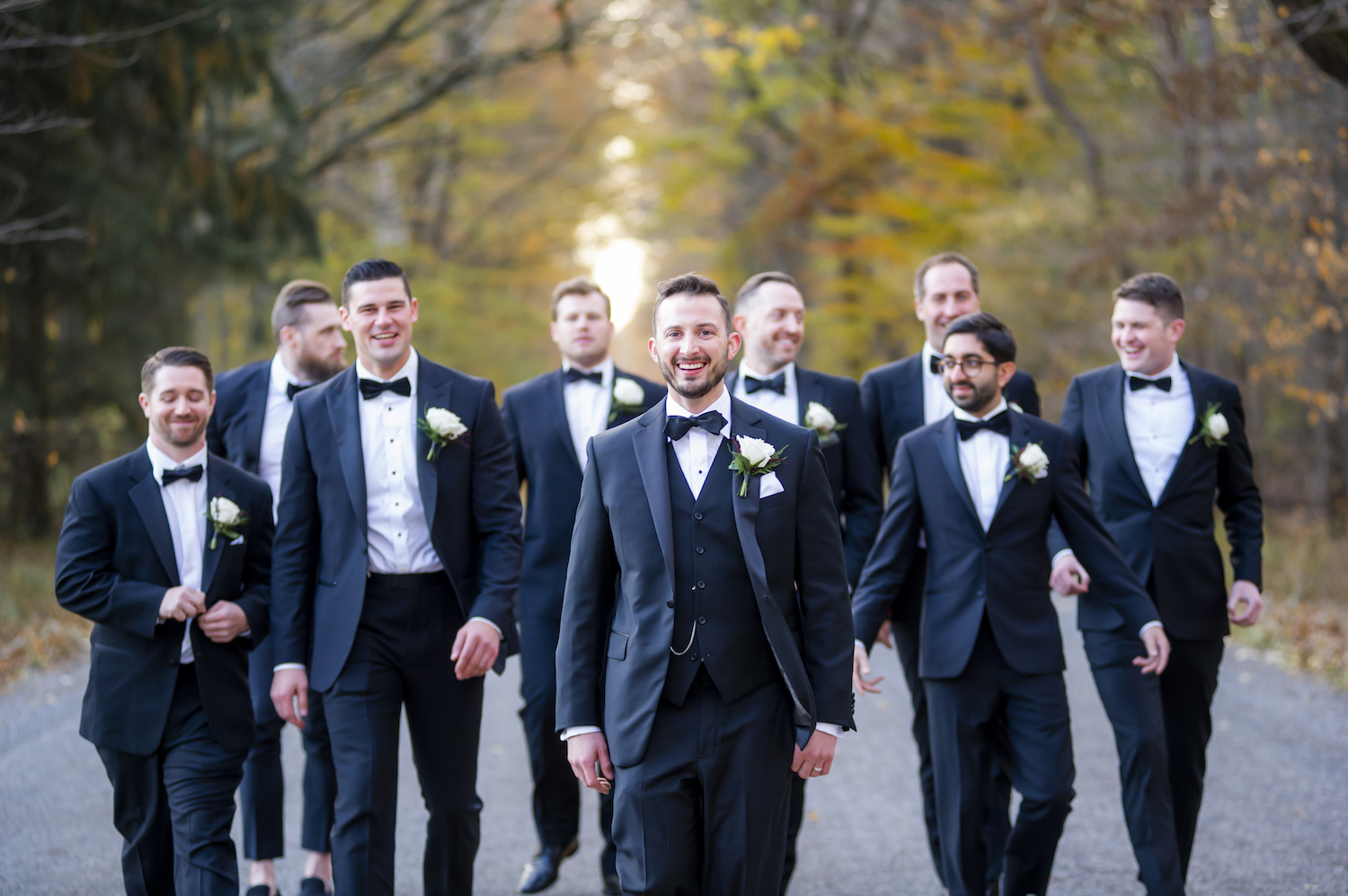 Groom and groomsman walking on road