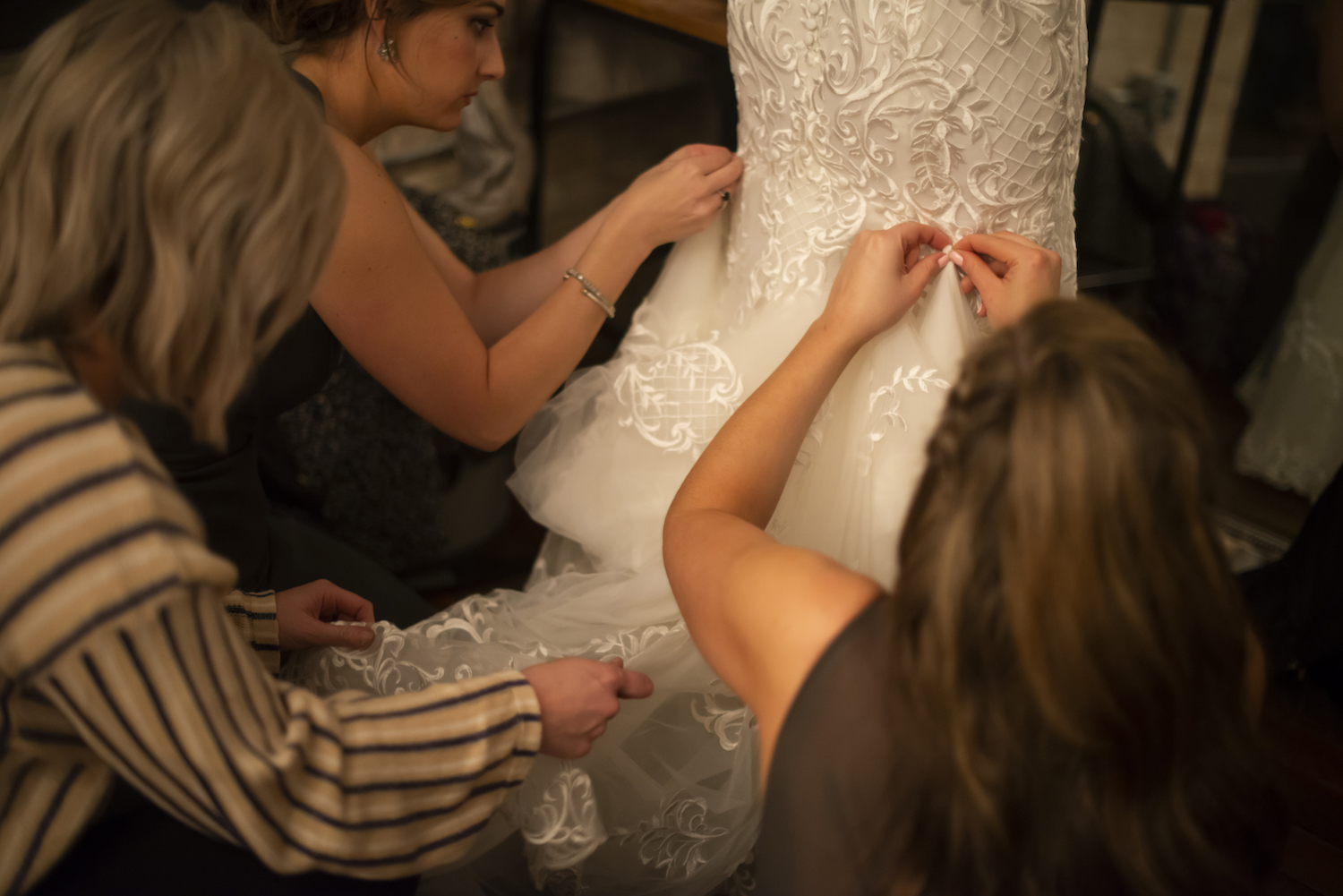 Bride's dress being buttoned up in back